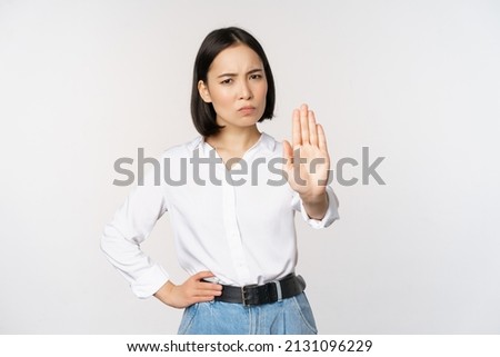 Portrait of young woman extending one hand, stop taboo sign, rejecting, declining something, standing over white background Royalty-Free Stock Photo #2131096229