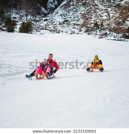 Family sledding on the snow and having fun in winter.
