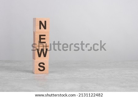 wooden cube on a concrete surface with text News. financial, investment, economy. copy space on right for you design, gray background.
