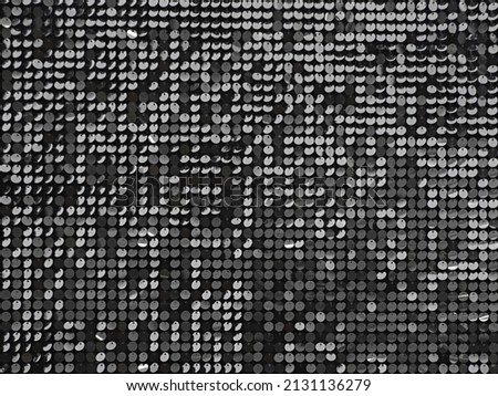 Abstract background with flickering and glittering silver metallic particles or sequins on the wall.
