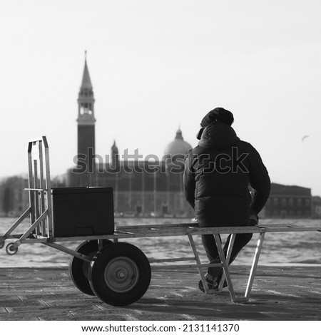 Picture of Man seated at a port in Venice in front of the sea in black and white
