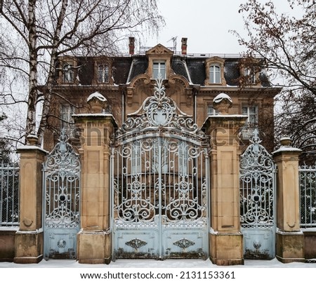 An old manor with beautiful gates is covered with snow. Strasbourg Royalty-Free Stock Photo #2131153361