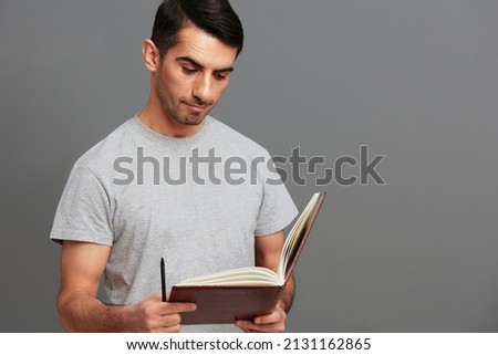 handsome man with a book in his hands in a gray T-shirt emotions isolated background