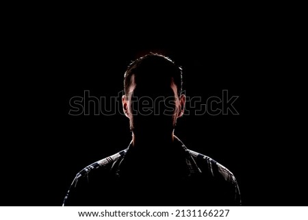 isolated dark male silhouette in the shadow, studio portrait Royalty-Free Stock Photo #2131166227