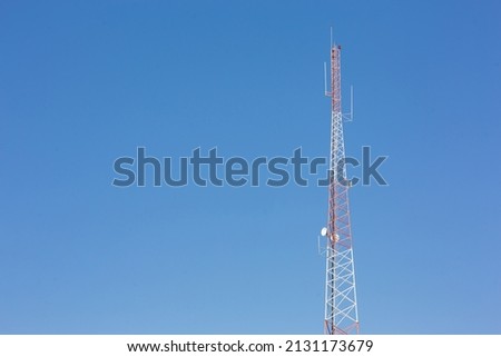 Telecommunication radio wave signal tower red white blue sky background