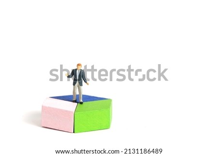 Miniature people toy figure photography. A shrugging businessman doing business presentation standing above wooden chart diagram. Isolated on white background. Image photo