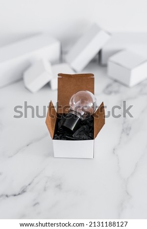 Think outside the box concept with idea lightbulb on top of white box on minimalist white marble background