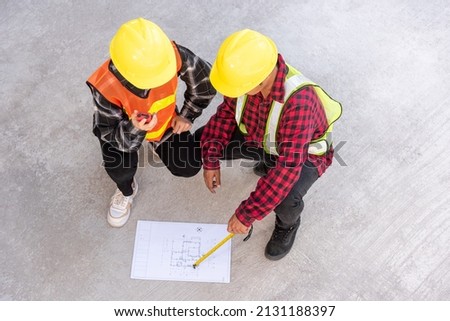 Architect and client discuss help create plan with blueprint of the building at construction site floor. Asian engineer foreman worker man and woman meeting talking on drawing paper project, top view