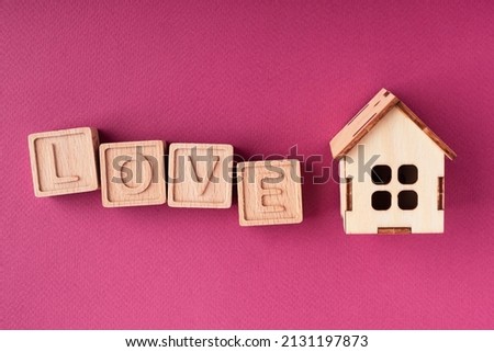The word love is made up of wooden cubes and a house, flat layout. The concept of family, love, relationships. Beautiful greeting card for Family Day, Valentine's Day, Mother's Day, Father's Day
