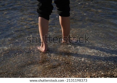 The feet of a young girl playing on the shore of the the Sea of Galilee Royalty-Free Stock Photo #2131198373