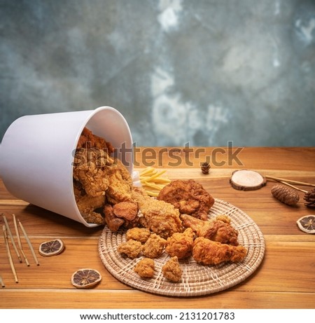 Fried chicken egg tart and french fries in paper bucket on wooden background, Deep fry Chicken and nuggets on wooden table. Royalty-Free Stock Photo #2131201783