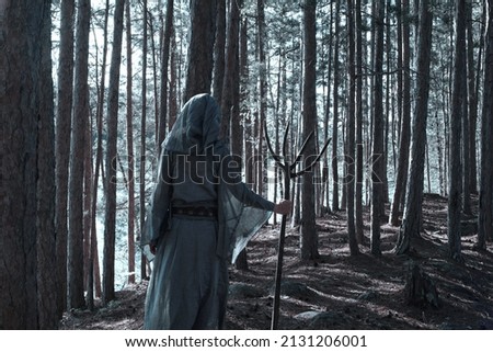 Shaman woman watching lake while hidden within a forest.        Royalty-Free Stock Photo #2131206001