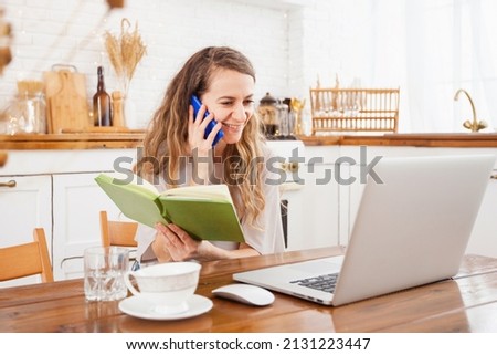 a young girl at home in the kitchen talking on the phone