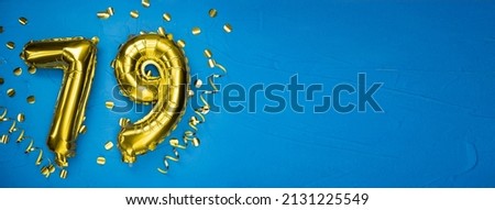 golden yellow foil balloon on blue concrete background number seventy nine. Birthday or anniversary card with 79 inscription. Anniversary celebration. Banner.