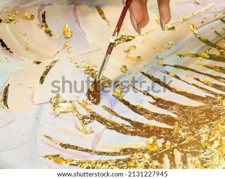 Handmade technique of applying the gold leaf. Gold gilding leaf decoration with brush, close up.