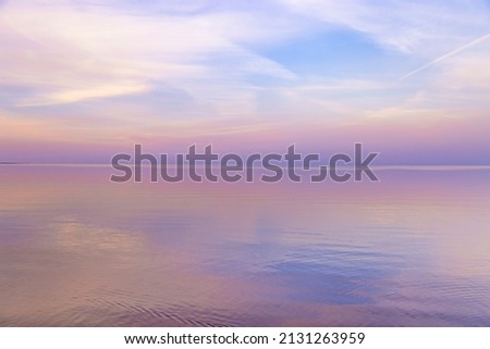 Sky background on sunset, colorful clouds. Nature abstract composition with reflections on sea water, natural blue pink purple shades of skyline. Nature environment. Royalty-Free Stock Photo #2131263959