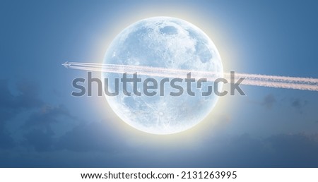 Jet airplane with trail of fuel on blue sky on the backgroun full moon "Elements of this image furnished by NASA" Royalty-Free Stock Photo #2131263995
