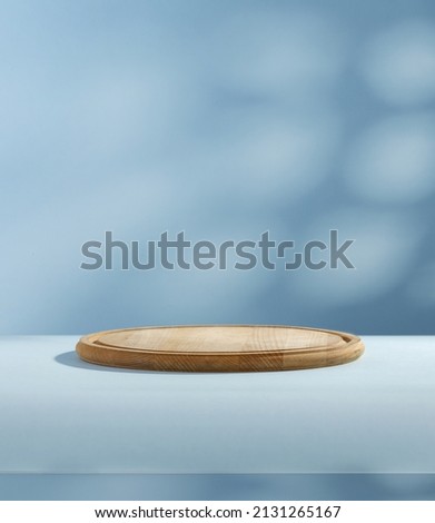 Wooden pedestal of free space for your decoration and blue wall with shadows. Dark interior and morning sun light. 