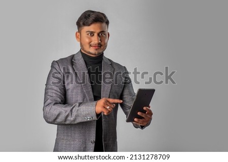 Young handsome young man, businessman holding and using smartphone or mobile or tablet phone on grey background 