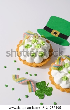 Sweet tasty dessert for St. Patrick's day. Two tartlets with whipped cream on a white background with colored jelly stripes, selective focus, text copy