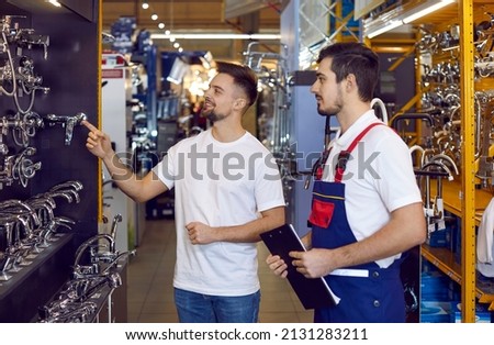 Happy man buying a faucet at a hardware store or shopping centre. Sales assistant with a clipboard helping a customer choose the best modern tap for his kitchen sink Royalty-Free Stock Photo #2131283211