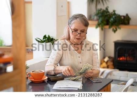 Elderly woman counts money and pays bills Royalty-Free Stock Photo #2131288287
