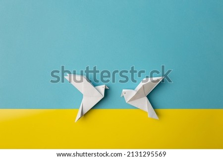 Two white birds as a symbol of peace on on blue and yellow pastel paper color for background. Copy space