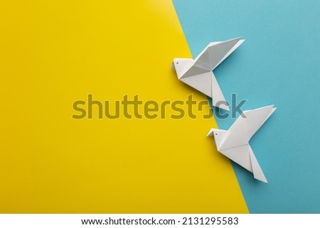Two white birds as a symbol of peace on on blue and yellow pastel paper color for background. Copy space