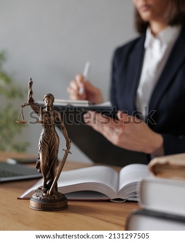 female lawyer or judge checks documents or a contract and makes notes in a notebook and phone, is engaged in the registration of divorce proceedings. work in a law firm in the office. european young