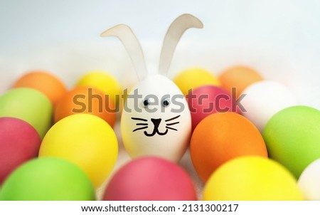 Funny bunny among colorful eggs. Holiday card. Easter background 