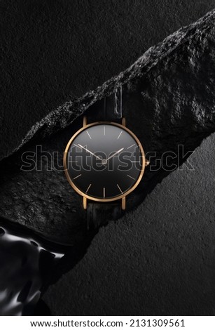 Luxurious gold watch with a black dial. A watch on a beautiful black background with black stones. Women's, Men's fashion Royalty-Free Stock Photo #2131309561