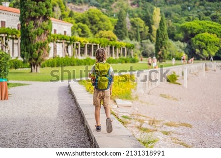 Boy tourist walking together in Montenegro. Panoramic summer landscape of the beautiful green Royal park Milocer on the shore of the the Adriatic Sea, Montenegro