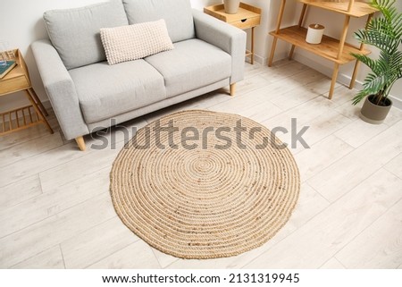 Trendy interior of living room with comfortable sofa and wicker carpet on light wooden floor Royalty-Free Stock Photo #2131319945