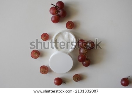 Organic cosmetics with grape seed oil. Skincare cosmetic product and grapes. Grapes and cosmetic butter in jar on white background. Flat lay top view copy space mockup