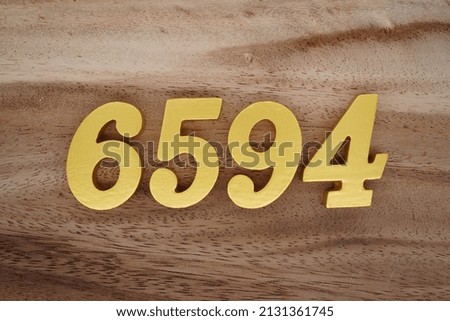 Wooden  numerals 6594 painted in gold on a dark brown and white patterned plank background.