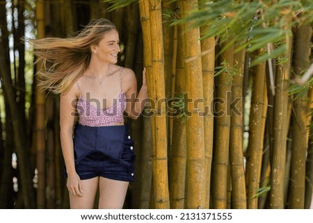 Portrait of smiling young woman at a park on a beautiful sunny day.  Green and nature background. Bamboo forest. High quality photo