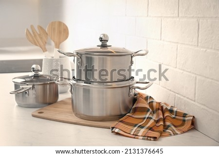 Set of stainless steel cookware and kitchen utensils on table near white brick wall Royalty-Free Stock Photo #2131376645