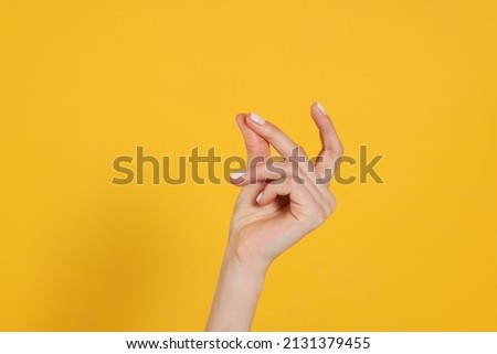 Woman snapping fingers on yellow background, closeup of hand Royalty-Free Stock Photo #2131379455