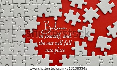 Top view of motivational quote on red cover - Believe in yourself, and the rest will fall into place. Jigsaw puzzle missing pieces background.