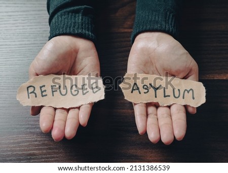 Hand with pieces of paper with words Refugee and Asylum message for help people concept NO WAR Russia and Ukraine