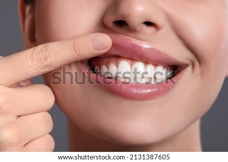 Young woman showing healthy gums on grey background, closeup
