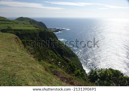 Scenic view along the north coast of Sao Miguel from Miradouro da Ponta do Escalvado with a strong sun reflection on the water, Sao Miguel, Azores, Portugal