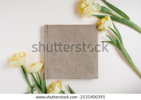 Composition with a wedding or family photo album, a bouquet of flowers of yellow tulips on a light background. Flat lay, top view still life. Royalty-Free Stock Photo #2131400391