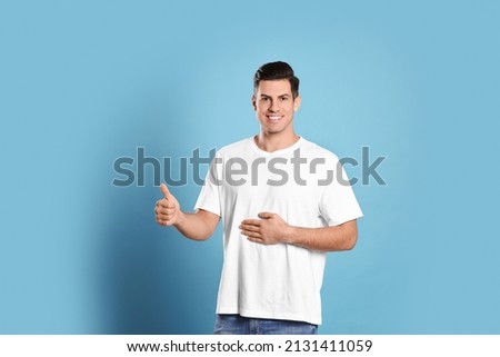 Happy healthy man touching his belly on light blue background Royalty-Free Stock Photo #2131411059
