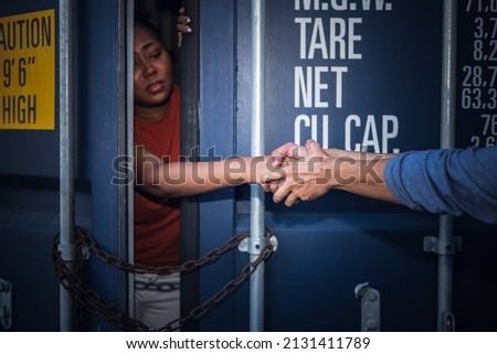 A person holding and helping to pull a several woman's hand which is inside a container, to human trafficking and illegal immigration concept. Royalty-Free Stock Photo #2131411789