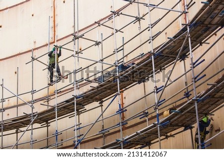 Worker male assembly in progress storage tank oil inspection scaffolding work at high in confined space.