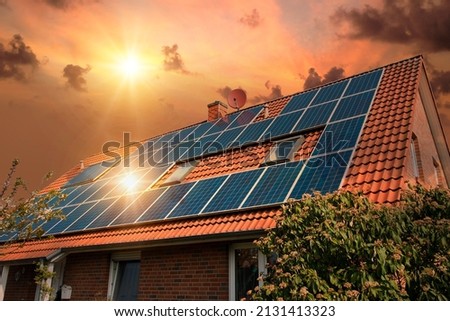Photo collage of solar panels, photovoltaics on the red roof of a house and a beautiful sky with the setting sun. Alternative electricity source. Concept of sustainable resources Royalty-Free Stock Photo #2131413323