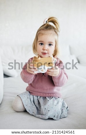 Small adorable girl holding wooden toy photo camera and take picture. Talented children