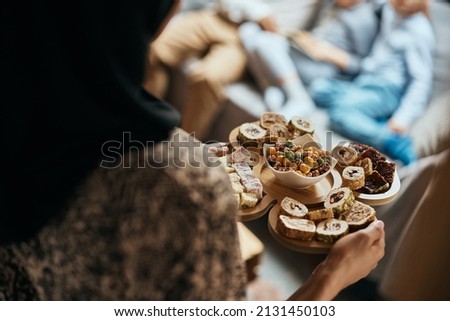 Close-up of Middle Eastern woman serving dessert at home.  Royalty-Free Stock Photo #2131450103