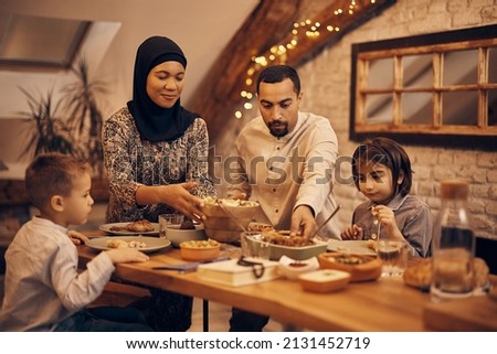 Muslim family gathering around dining table for Ramadan dinner.  Royalty-Free Stock Photo #2131452719